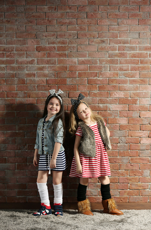 Two stylish little girls on wall backgroundの写真素材