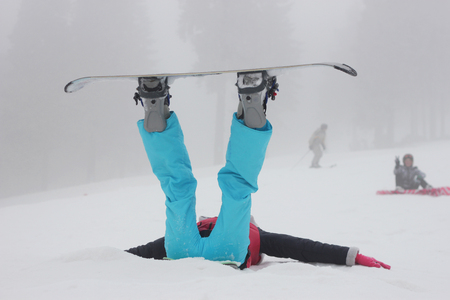 Girl snowboarder falling over white snow backgroundの写真素材