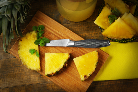 Juicy pineapple slices with fresh mint on wooden cutting boardの写真素材