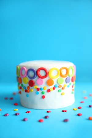 Birthday cake with colorful decorations on blue background.