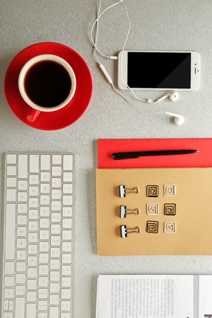 Workplace with mobile phone, keyboard and stationery on grey tableの写真素材