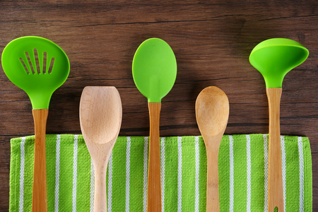 Set of kitchen tools with green napkin on wooden tableの写真素材
