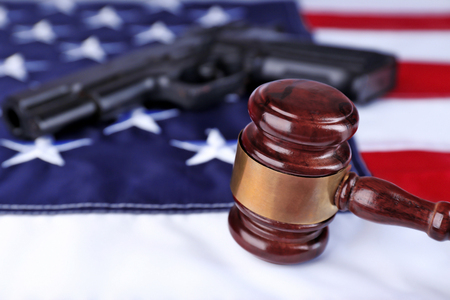 Gavel with gun on background of USA flagの写真素材
