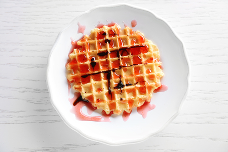 Plate of waffles with chocolate glaze on wooden backgroundの写真素材
