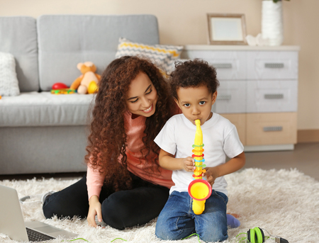 Little boy and a young girl playing  with musical toys on the floorの写真素材