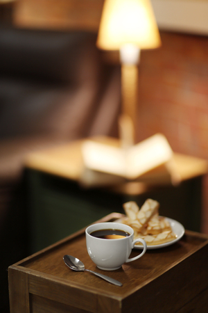 White cup of the coffee and biscuits on a wooden table in a dark room..の写真素材