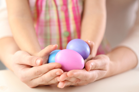 Hands of mother and daughter holding painted Easter eggs closeupの写真素材