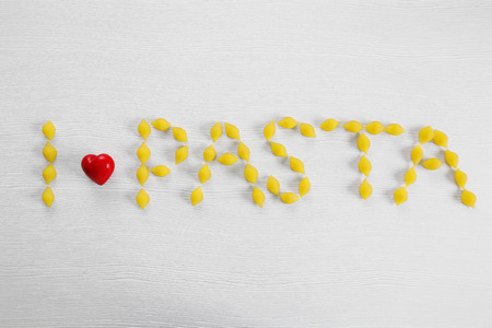 Phrase I LOVE PASTA from fresh uncooked pasta on wooden background