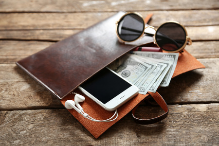 Leather purse with mobile phone, glasses and dollar banknotes on wooden tableの写真素材