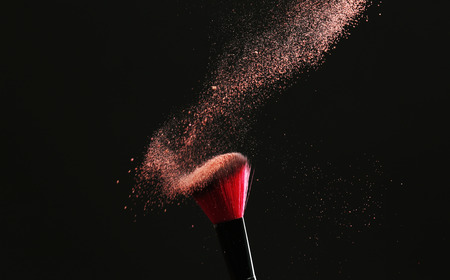 Makeup brush with flying powder on black backgroundの写真素材