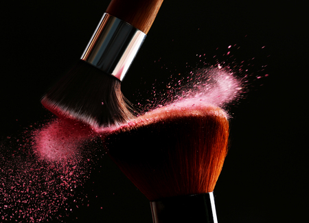 Makeup brushes with flying powder on black backgroundの写真素材
