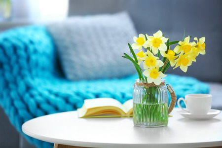 Yellow narcissus on white table in room interiorの写真素材