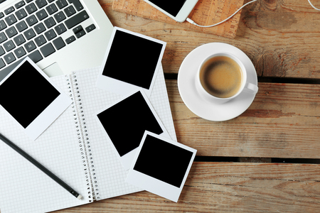Laptop, notebook and photos on wooden backgroundの写真素材
