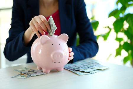 Woman putting money in piggy bankの写真素材