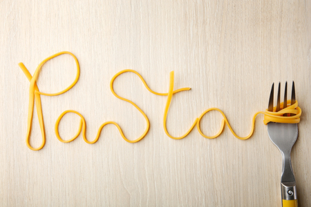 Word PASTA made of cooked spaghetti with fork on wooden backgroundの写真素材