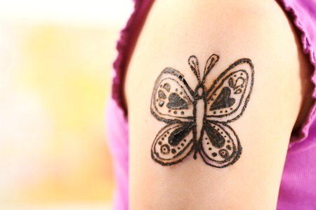 Image of butterfly painted with henna on girl's arm closeupの写真素材