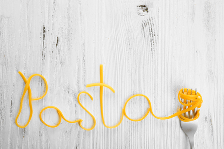 Word PASTA made of cooked spaghetti with fork on wooden backgroundの写真素材