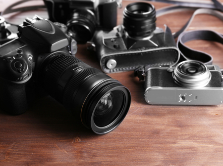Modern and retro cameras on wooden background
