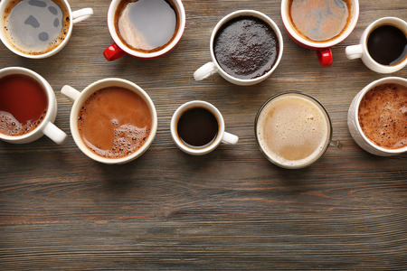 Different cups of coffee on wooden table, top viewの写真素材