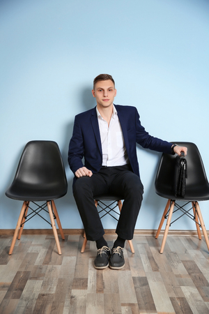 Young man in suit sitting on chair and waiting for job interviewの写真素材