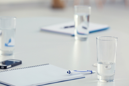 Glasses of water and notebooks on the table in the office, close-upの写真素材