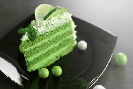 Piece of delicious creamy lime cake on black plate closeupの写真素材
