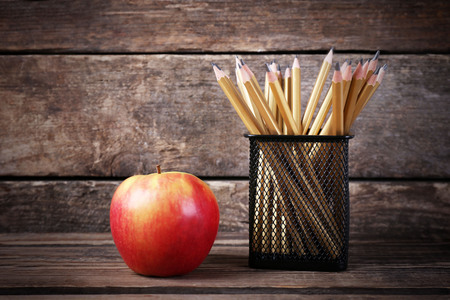 Set of pencils in metal holder and fresh apple on wooden backgroundの写真素材