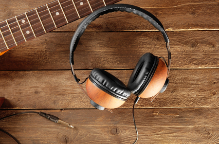 Headphones and guitar on wooden backgroundの写真素材