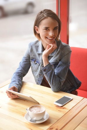 Young woman sitting in cafe with smartphoneの写真素材