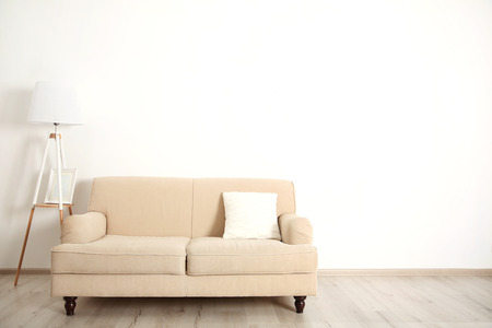 Beige couch and lamp on white wall backgroundの写真素材