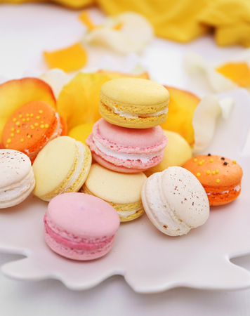Plate with fresh macaroons and rose petals on light backgroundの写真素材