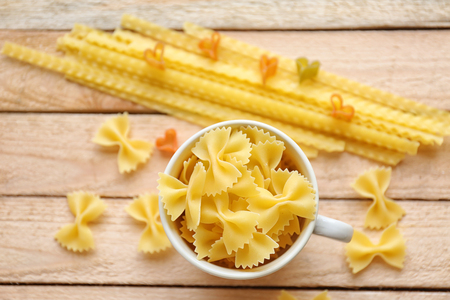 Pasta farfalle in cup on wooden table backgroundの写真素材