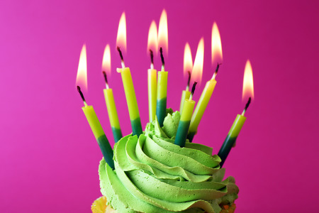 Birthday cupcake with candles on pink backgroundの写真素材