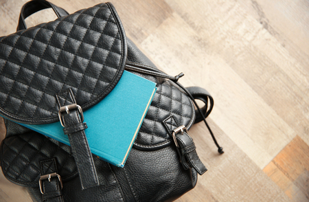 Leather backpack and book on wooden backgroundの写真素材