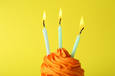 Birthday cupcake with candles on yellow backgroundの写真素材