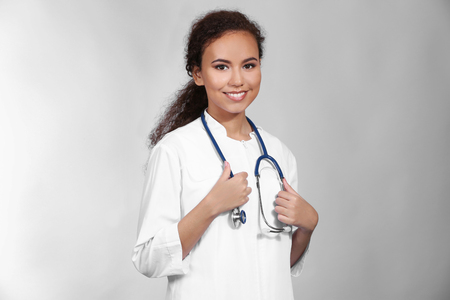 Beautiful African American female doctor on grey backgroundの写真素材
