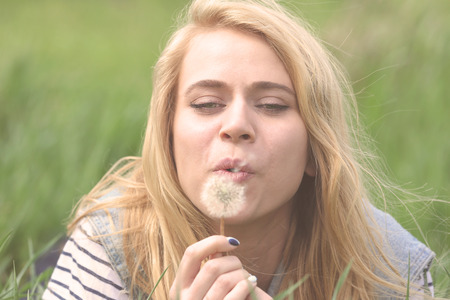 Young beautiful woman with blowball on green grassの写真素材