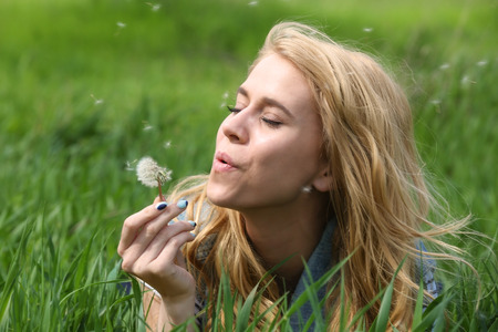 Young beautiful woman with blowball on green grassの写真素材