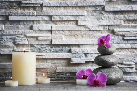Composition of spa pebbles, flowers and candles on grey brick wall backgroundの写真素材