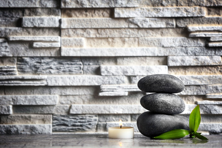 Composition of spa pebbles, candle and bamboo leaf on grey wall backgroundの写真素材