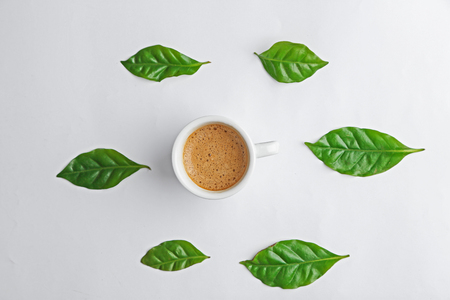 Cup of tasty coffee with leaves on white backgroundの写真素材