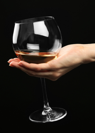 Female hand holding glass of champagne on black backgroundの写真素材