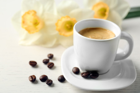 Cup of coffee with narcissus on wooden tableの写真素材