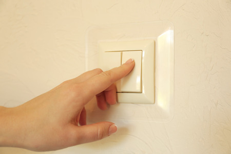A finger is turning on a light switch