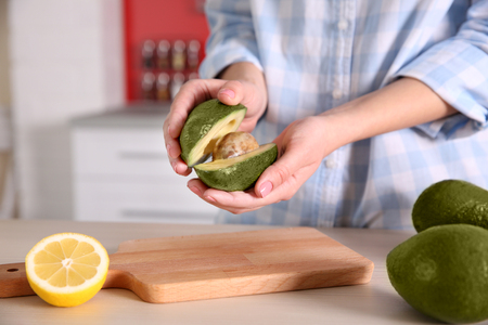 Woman holding fresh avocado in kitchenの写真素材
