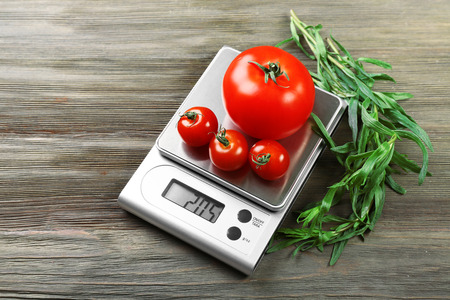 Tomatoes with digital kitchen scales on wooden backgroundの写真素材