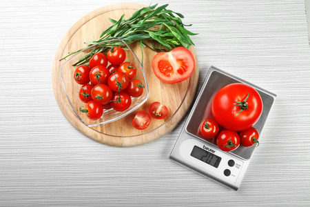 Tomatoes with digital kitchen scales on wooden backgroundの写真素材