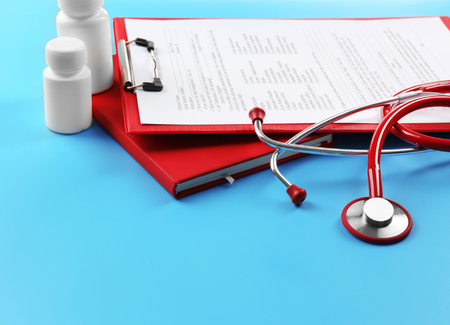 Red stethoscope and pills on blue backgroundの写真素材