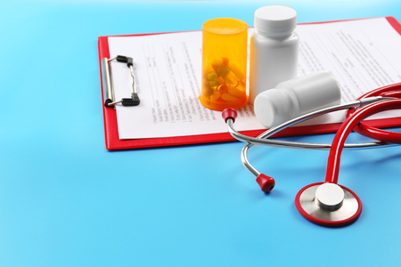Red stethoscope and pills on blue backgroundの写真素材