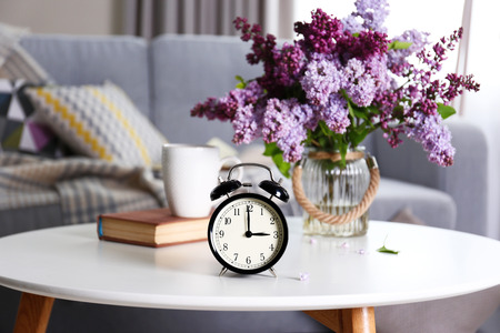 Alarm clock with lilac bouquet on tableの写真素材